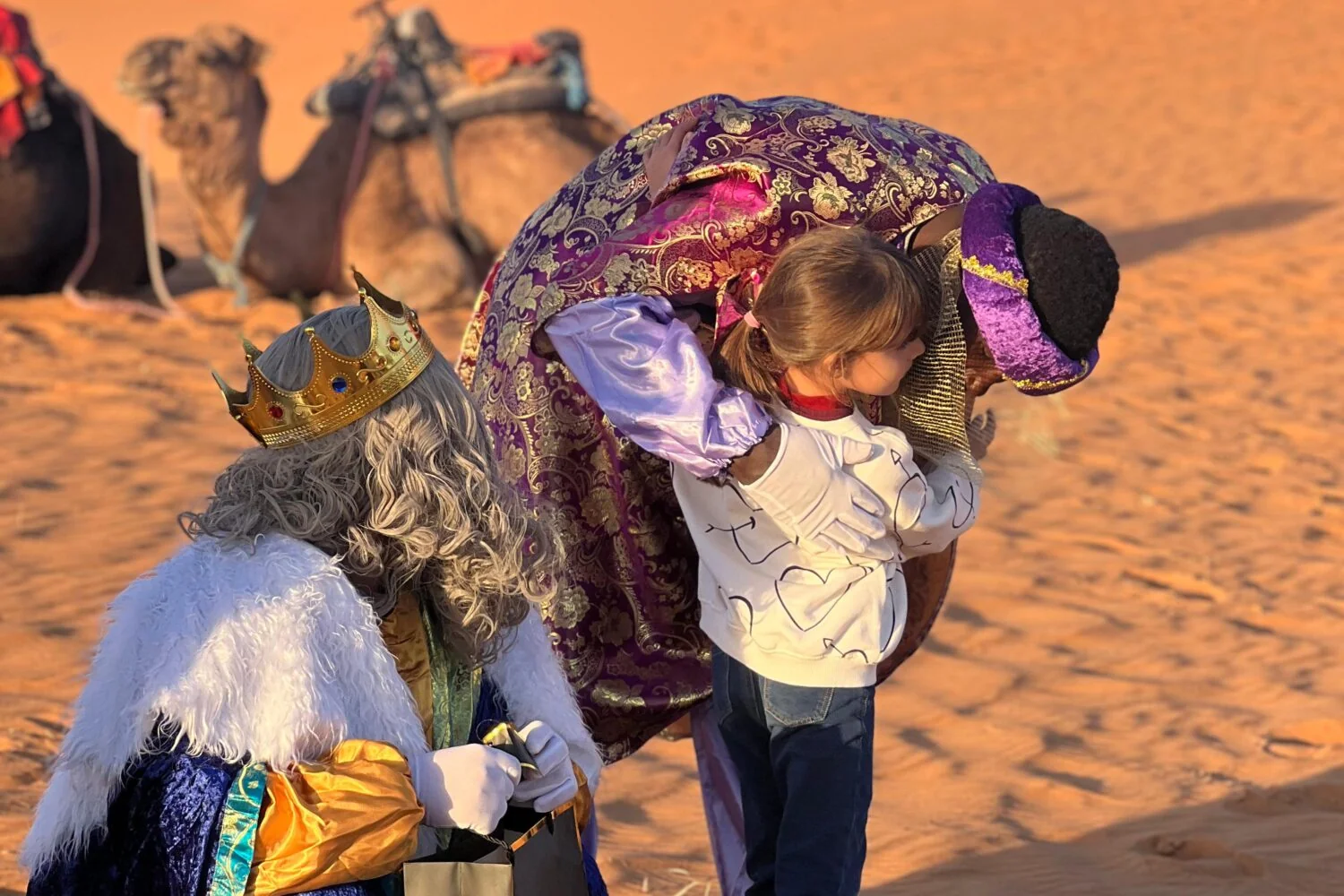 Una niña recibe a los Reyes Magos y sus regalos en las dunas