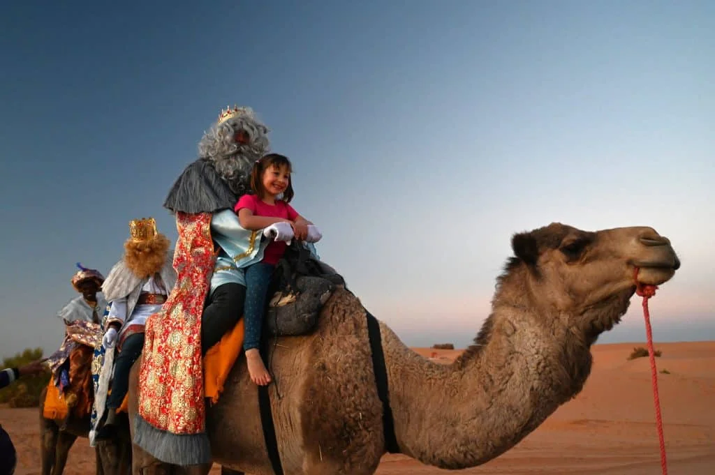 Una niña a camello con los Reyes Magos en el desierto